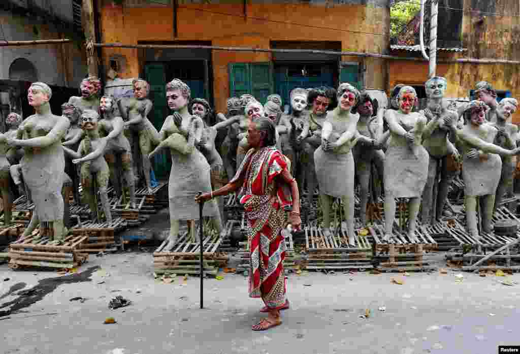 A woman walks past semi-finished clay idols of the Hindu mythological characters &#39;Dakinis&#39; and &#39;Yoginis,&#39; at a roadside workshop ahead of the Kali Puja festival in Kolkata, India.