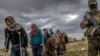 Men suspected of being Islamic State fighters wait to be searched by members of the Kurdish-led Syrian Democratic Forces (SDF) after leaving the IS group's last holdout of Baghuz, Syria, Feb. 27, 2019. 