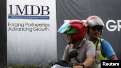 FILE - Motorcyclists pass a 1 Malaysia Development Berhad (1MDB) billboard at the Tun Razak Exchange development in Kuala Lumpur, Malaysia, Feb. 3, 2016. 