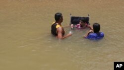 A Venezuelan family, one in a wheelchair, cool off and bathe in the Branco River in Boa Vista, Roraima state, Brazil, March 11, 2018. Some Venezuelans arrive to Brazil wearing baggy clothes, have emaciated faces and complain of medical issues ranging from children with measles to diabetics with no insulin. 