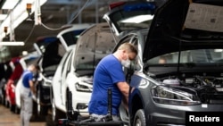 FILE - A worker wears a protective mask at the Volkswagen assembly line after VW re-started Europe's largest car factory after a coronavirus shutdown, in Wolfsburg, Germany, April 27, 2020.