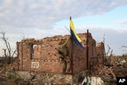 ARCHIVO - Un comandante de la unidad de asalto de la 3.ª Brigada de Asalto que se hace llamar 'Fedia' iza la bandera ucraniana como símbolo de liberación de la aldea de primera línea de Andriivka, región de Donetsk, Ucrania, el sábado 16 de septiembre de 2023.