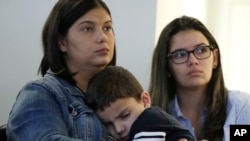 Sirlen Costa of Brazil holds her son Samuel, 5, as her niece Danyelle Sales, right, looks on during a news conference, Aug. 26, 2019, in Boston. Costa brought her son to the United States seeking treatment for his short bowel syndrome.