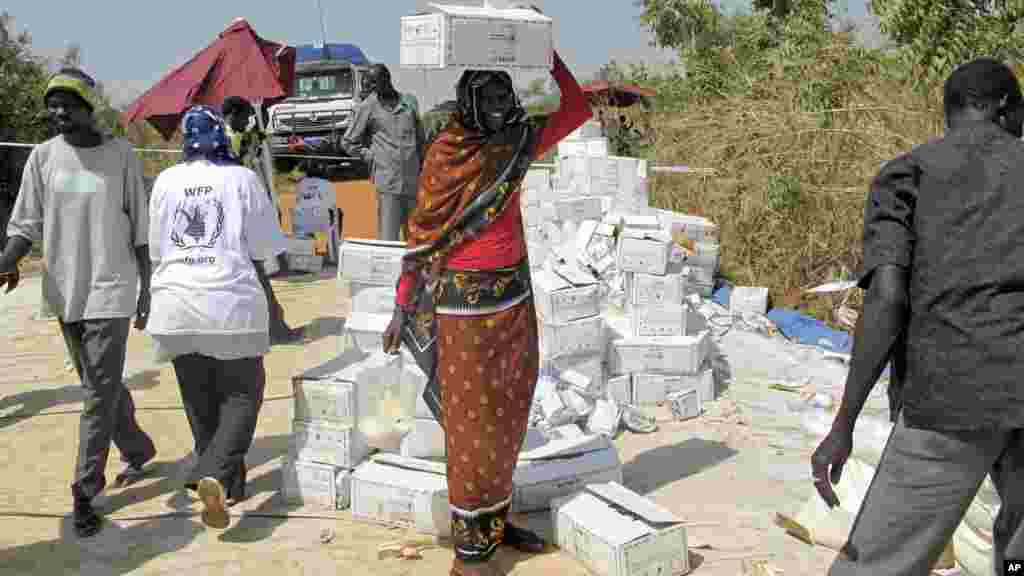 Uma mulher deslocada de guerra caminha com uma caixa de comida na cabeça, no campo de refugiados da ONU. Juba, Dez. 23, 2013. (WFP)