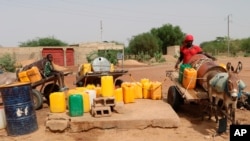 Residents fill up water containers in Dori, Burkina Faso, July 7, 2021. Violence by fighters linked to al-Qaida and the Islamic State in Burkina Faso is on the rise, and with it, so is the recruitment of child soldiers, according to reports.