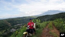 Seorang petani naik sepeda motor di jalan tanah dengan latar belakang Gunung Gede Pangrango, Bogor, Jawa Barat. Foto diambil 8 Maret 2017.