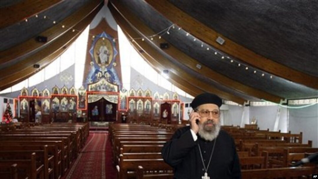 Father Girguis Lucas uses his cellphone before addressing reporters, inside the Coptic church Sainte Marie Saint Marc of Chatenay-Malabry, south of Paris, 04 Jan 2011.
