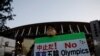 Seorang pengunjuk rasa yang menuntut pembatalan Olimpiade Tokyo 2020 memegang spanduk di depan Stadion Nasional, stadion utama Olimpiade dan Paralimpiade Tokyo 2020. (Foto: Reuters)