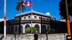 FILE - A man walks beside Canada's embassy in Havana, Cuba.