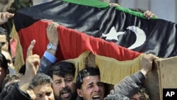 Mourners carry a coffin draped in the opposition flag at a funeral for some of those killed by Thursday's airstrike on rebel forces in Benghazi,Apr 8 2011