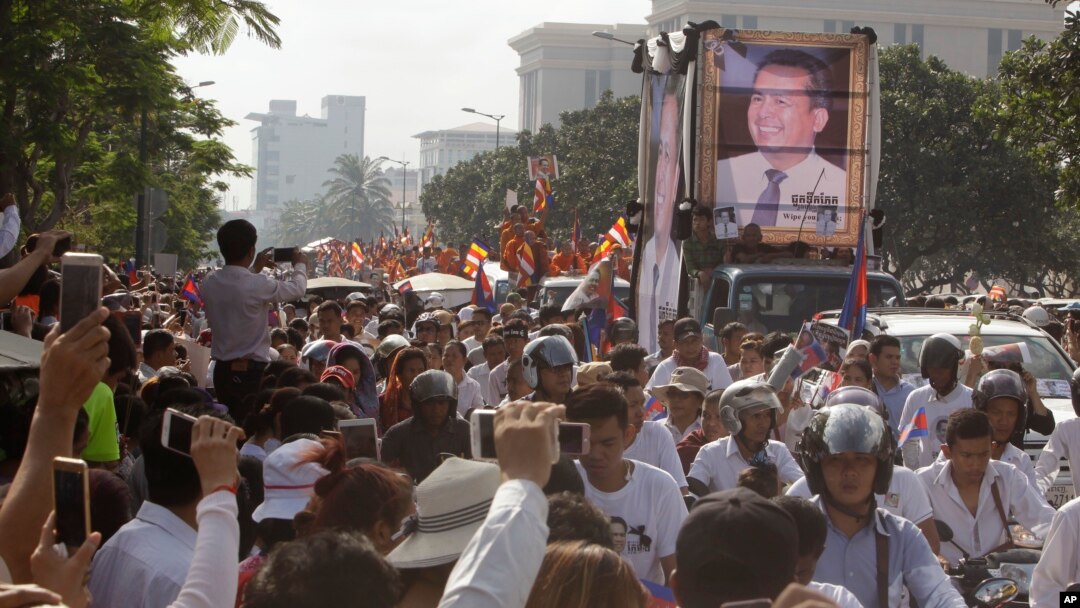Mourners take photos as they watch the funeral procession for Cambodian leading government critic Kem Ley in Phnom Penh, July 24, 2016. 