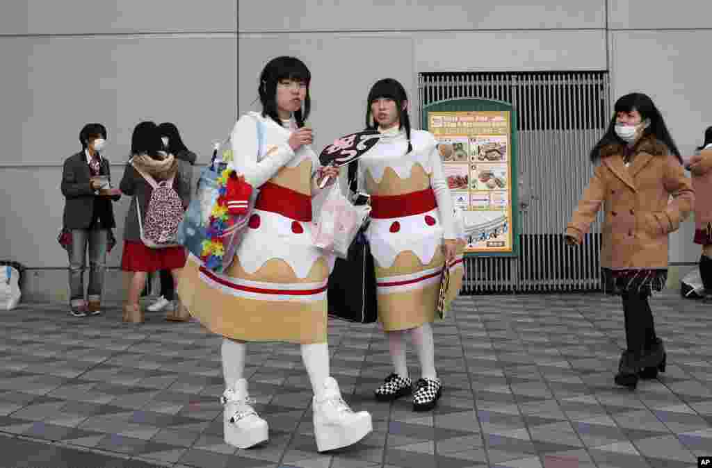 Concertgoers wearing cake-shaped decoration wait outside Tokyo Dome before the concert of a Japanese pop idol group in Tokyo.