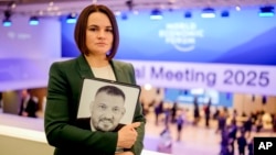 FILE – Belarusian opposition leader Sviatlana Tsikhanouskaya holds a photo of her imprisoned husband, Syarhei Tsikhanouski, at the annual World Economic Forum in Davos, Switzerland, on Jan. 21, 2025.