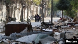 Civilians walk past debris from damaged buildings in the rebel held area of Old Aleppo, Syria, Nov. 14, 2016.