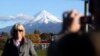 FILE - A man takes a picture of his wife with Taranaki Maunga, previously known as Mount Taranaki, in the background in New Plymouth, New Zealand, Sept. 26, 2011.