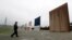 FILE - A Border Patrol agent walks towards prototypes for a border wall in San Diego, California, Feb. 5, 2019. 