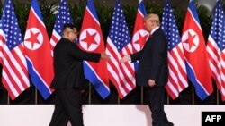 지난 6월 12일 싱가포르에서 열린 첫 미-북 정상회담에서 도널드 트럼프 미국 대통령과 김정은 북한 국무위원장이 악수를 하기 위해 서로에게 손을 내밀고 있다.