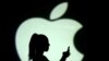  ARCHIVO - Silueta de un usuario de celular frente a una proyección del logo de Apple.