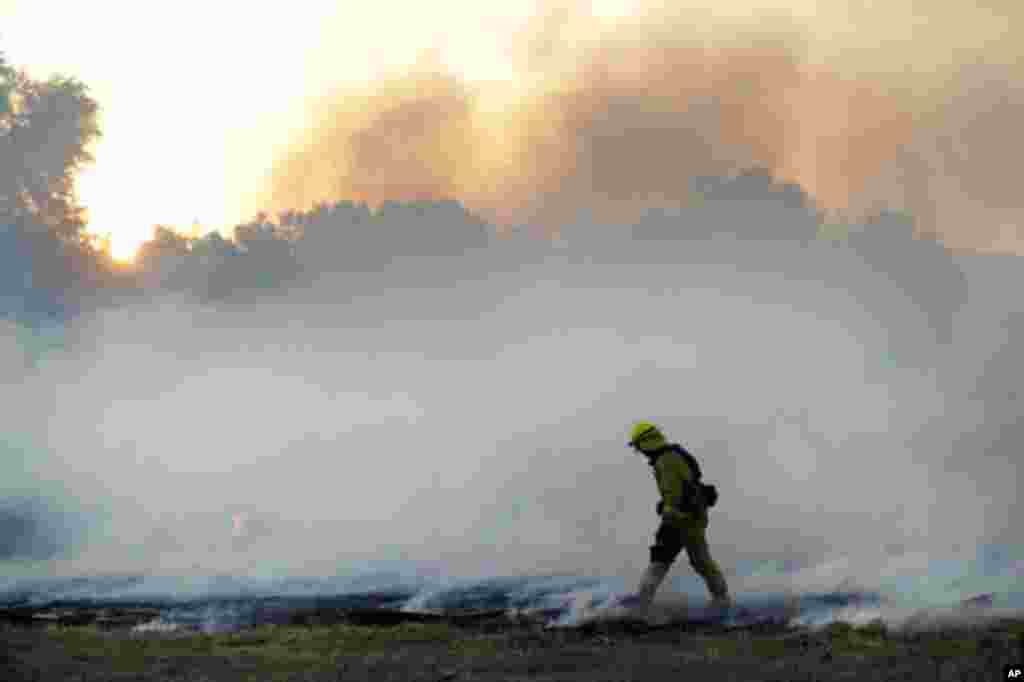 Un bombero palea arena en los puntos calientes mientras lucha contra el Incendio 46.