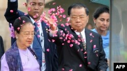 Myanmar military ruler Senior General Than Shwe (R) sprinkles rose petals next to his wife Daw Kyaing Kyaing (L) as they pay tribute at Rajghat, a memorial for Mahatma Gandhi, during a visit in New Delhi on July 27, 2010. Than Shwe received a red-carpet w