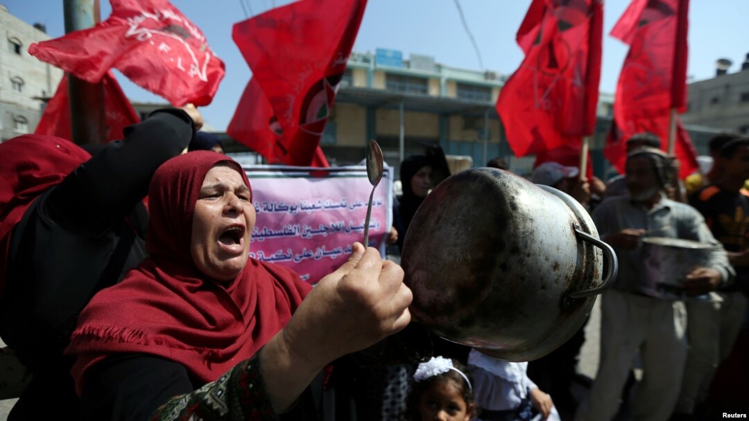 Seorang perempuan Palestina memegang panci dalam unjuk rasa memprotes keputusan AS untuk mengurangi bantuan untuk badan PBB yang membantu pengungsi Palestina, UN Relief and Works Agency (UNRWA), di luar pusat distribusi antuan di Khan Younis, di selatan Jalur Gaza, 4 Septembe 2018.