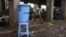FILE - A boy runs past a dispenser containing water mixed with disinfectant, east of Mbandaka, DRC, May 23, 2018.