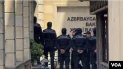 Farid Mehralizada, an economist and journalist for Radio Free Europe/Radio Liberty’s Azerbaijani Service, is guarded by police in this undated photo.