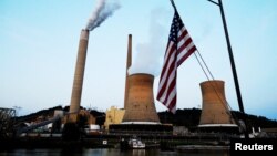 FILE - A U.S. flag flies on tugboat as it passes the coal-fired Mitchell Power Plant on the Ohio River, in Moundsville, West Virginia, Sept. 10, 2017.