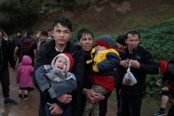 FILE - Migrants walk on a dirt road following their arrival on a dinghy on a beach near the village of Skala Sikamias, after crossing part of the Aegean Sea from Turkey to the island of Lesbos, Greece, March 5, 2020.