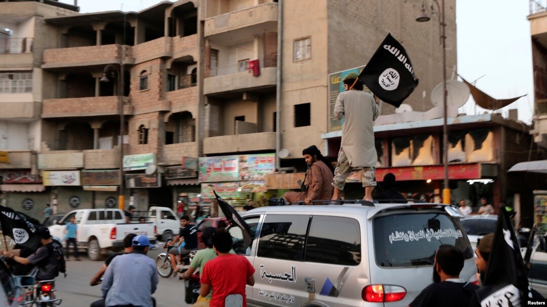 FILE - Members loyal to the Islamic State in Iraq and the Levant wave flags as they drive around Raqqa, June 29, 2014.