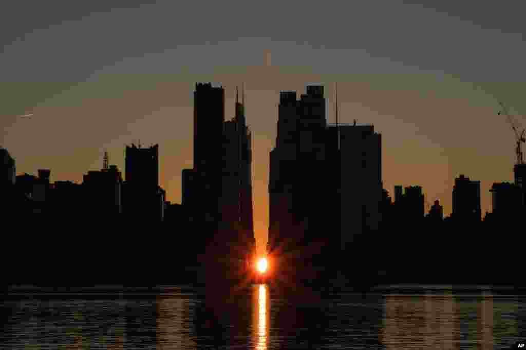The sun rises through the middle of buildings long 42nd street in New York's Manhattan borough during a phenomenon known as Manhattanhenge as viewed from Weehawken, New Jersey.