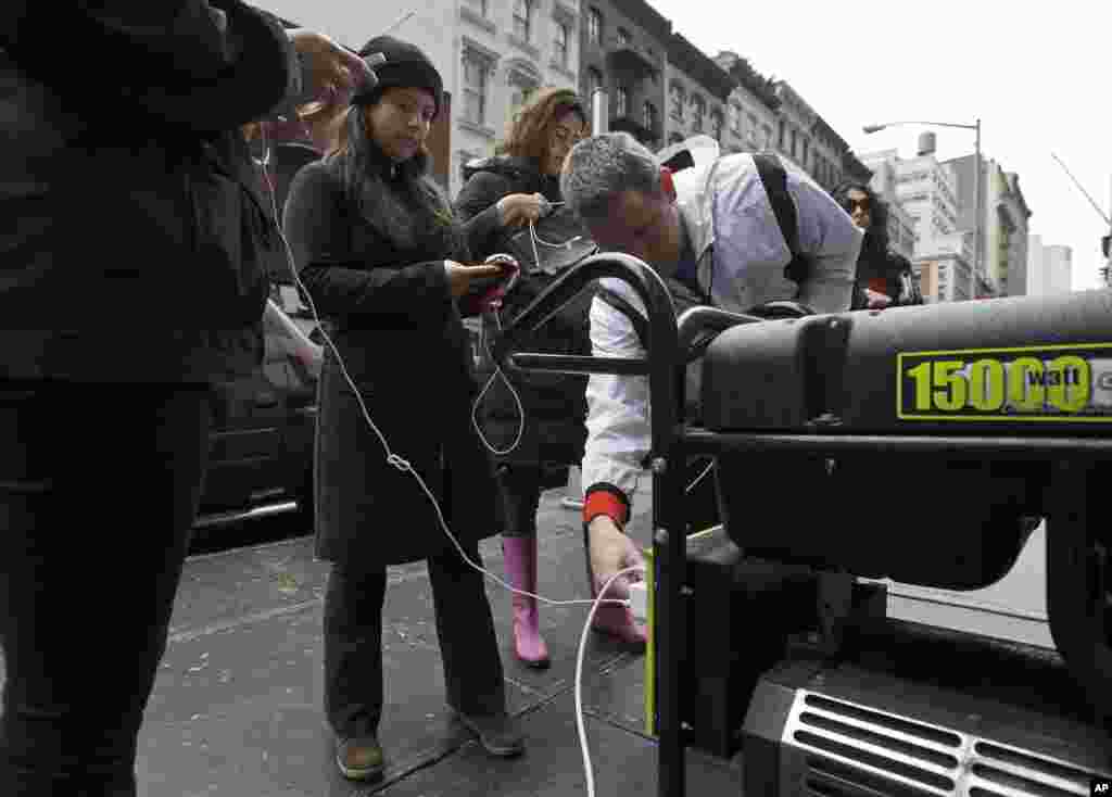 People in New York's Tribeca neighborhood, without power because of superstorm Sandy, wait for a chance to charge their mobile phones on an available generator setup on a sidewalk, Tuesday, Oct. 30, 2012. 