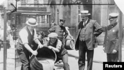 New York City Deputy Police Commissioner John A. Leach (R) watches agents pour liquor into a sewer following a raid during the height of prohibition in an undated photo held by the Library of Congress. 