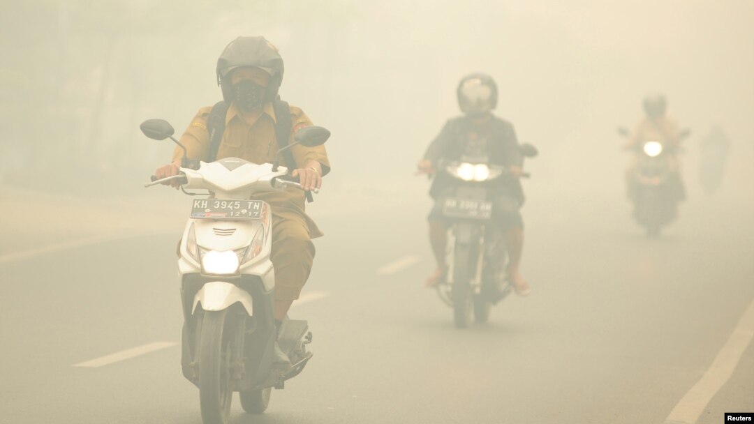 Warga mengendarai motor di tengah kabut asap kebakaran hutan yang menyelimuti Kota Palangkaraya, Kalimantan Tengah, 27 Oktober 2015. (Foto: Antara via Reuters)