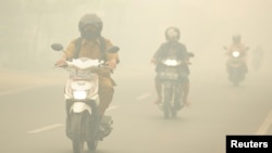 Warga mengendarai motor di tengah kabut asap kebakaran hutan yang menyelimuti Kota Palangkaraya, Kalimantan Tengah, 27 Oktober 2015. (Foto: Antara via Reuters)