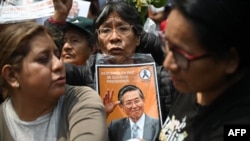 Una mujer sostiene un retrato del fallecido expresidente peruano Alberto Fujimori mientras espera la llegada del ataúd al cementerio Campo Fe de Huachipa durante su funeral de estado en Lima el 14 de septiembre de 2024.