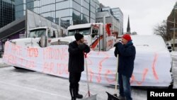 Demonstran mengobrol setelah membersihkan salju dari jalan ketika pengemudi truk dan pendukung terus memprotes mandat vaksin COVID-19 di Ottawa, Ontario, Kanada, 3 Februari 2022. (Foto: REUTERS/Blair Gable)