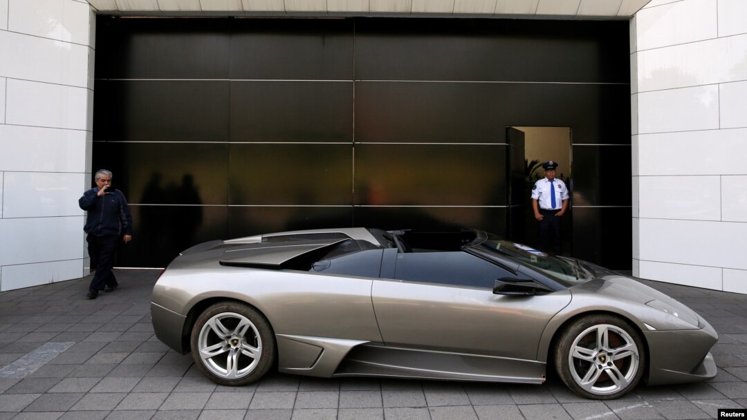 Un policía hace guardia cerca de un Lamborghini Murciélago 2007, parte de una flota de vehículos confiscados por el gobierno de políticos y del crimen organizado, que serán subastados en Ciudad de México. Mayo 21 de 2019.