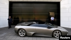 Un policía hace guardia cerca de un Lamborghini Murciélago 2007, parte de una flota de vehículos confiscados por el gobierno de políticos y del crimen organizado, que serán subastados en Ciudad de México. Mayo 21 de 2019.