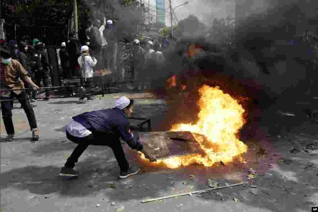 Para pengunjuk rasa mencoba memadamkan api dari ban yang terbakar di Jakarta, Rabu, 22 Mei 2019. (Foto:&nbsp;AP/Dita Alangkara)