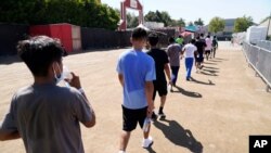 Niños migrantes caminan juntos después de un partido de fútbol en un refugio de emergencia para niños migrantes el viernes 2 de julio de 2021 en Pomona, California.