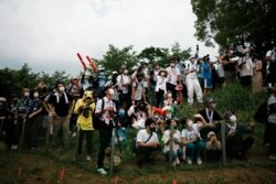 Masked fans watch from a hillside during the men's cross country mountain bike competition at the 2020 Summer Olympics, Monday, July 26, 2021, in Izu, Japan. (AP Photo/Thibault Camus)