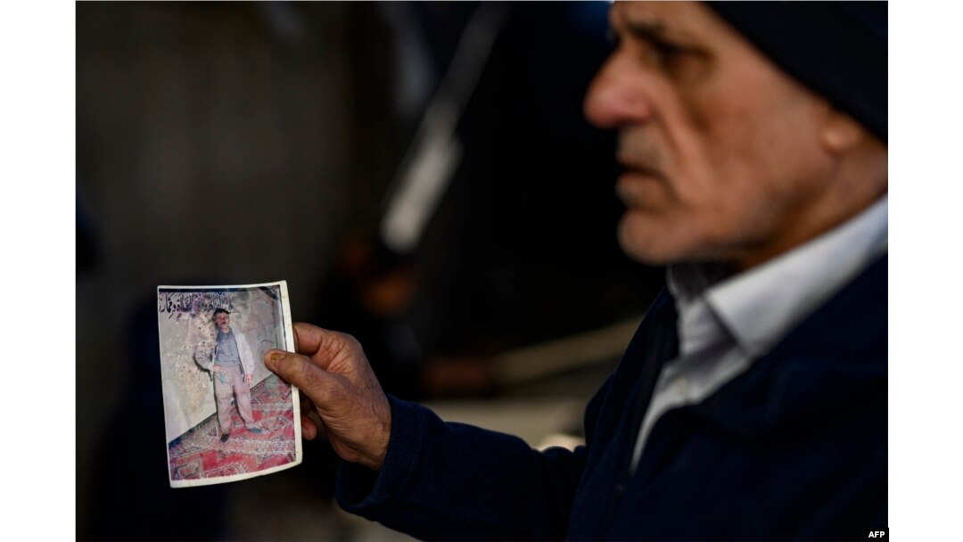 Mehmet Erturk, a Turk imprisoned in a Syrian prison, shows pictures during an interview with AFP journalists at his house in the village of Magaracik in Kilis on Dec. 13, 2024.