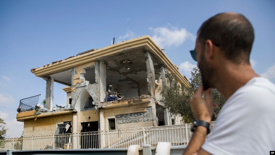 A man watches a house that was hit by a missile fired from Gaza Strip, in the city of Beersheba, southern Israel, Wednesday, Oct. 17, 2018. A medical service said a woman and her three children, whose home was struck, were being treated for shock after they fled to their shelter upon being awoken by warning sirens.