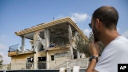 A man watches a house that was hit by a missile fired from Gaza Strip, in the city of Beersheba, southern Israel, Wednesday, Oct. 17, 2018. A medical service said a woman and her three children, whose home was struck, were being treated for shock after they fled to their shelter upon being awoken by warning sirens.