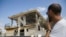 A man watches a house that was hit by a missile fired from Gaza Strip, in the city of Beersheba, southern Israel, Wednesday, Oct. 17, 2018. A medical service said a woman and her three children, whose home was struck, were being treated for shock after they fled to their shelter upon being awoken by warning sirens.