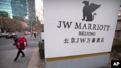 Seorang petugas layan antar berjalan dekat pintu masuk Hotel JW Marriott di Beijing, China, 11 Januari 2018.