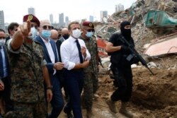 FILE - French President Emmanuel Macron, center, visits the devastated site of the explosion at the port of Beirut, Lebanon, Aug.6, 2020.