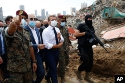 French President Emmanuel Macron, center, visits the devastated site of the explosion at the port of Beirut, Lebanon, Aug.6, 2020.