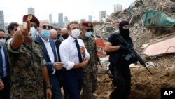 French President Emmanuel Macron, center, visits the devastated site of the explosion at the port of Beirut, Lebanon, Aug. 6, 2020. 